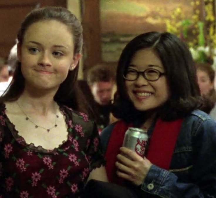 two women standing next to each other holding drinks