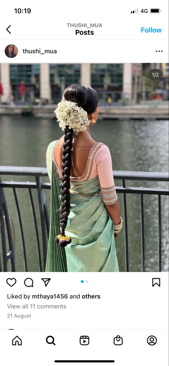 the back of a woman's head with long braids and flowers in her hair