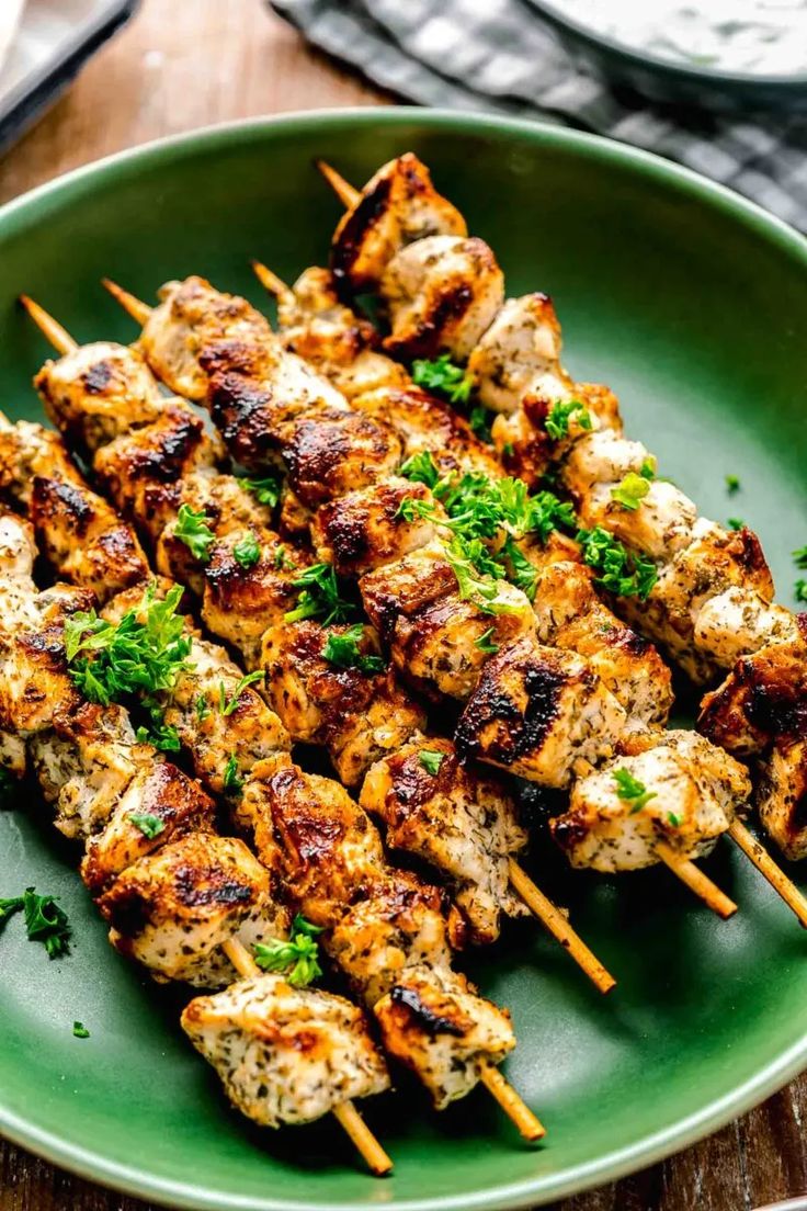 chicken skewers with parsley on a green plate