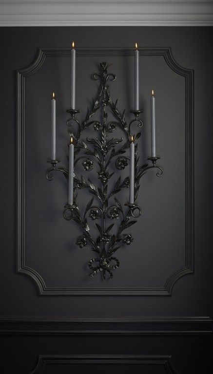 a wall mounted candle holder with five candles in the shape of an ornate flower and leaves