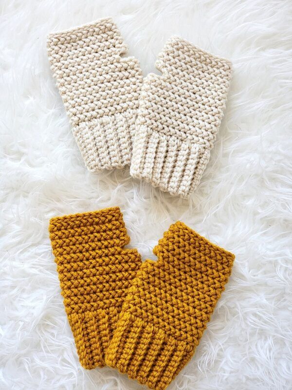 two knitted mittens sitting on top of a white furnishing covered floor