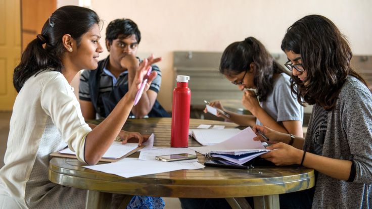 a group of people sitting at a table with papers and pens in front of them