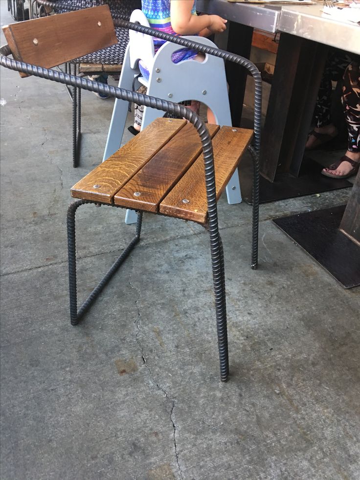 a child sitting on a bench made out of wooden slats and metal barstools