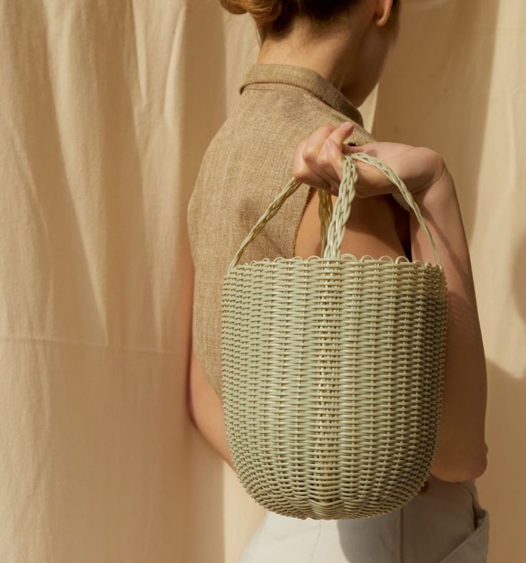 a woman is holding a wicker bag