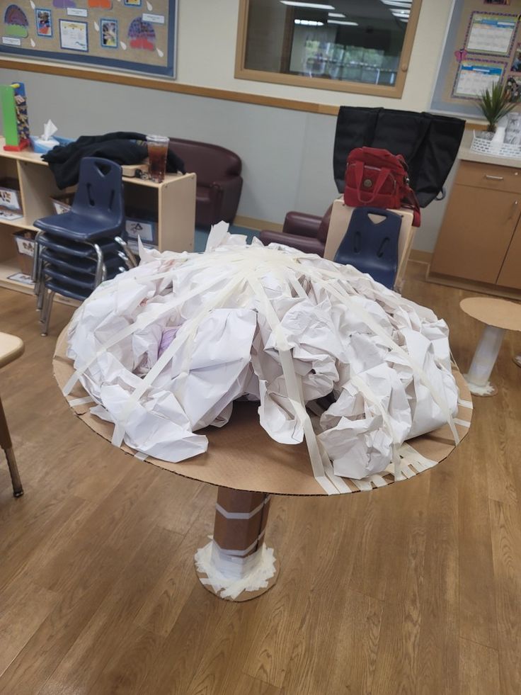 a table that has been made out of toilet paper and some chairs in the background