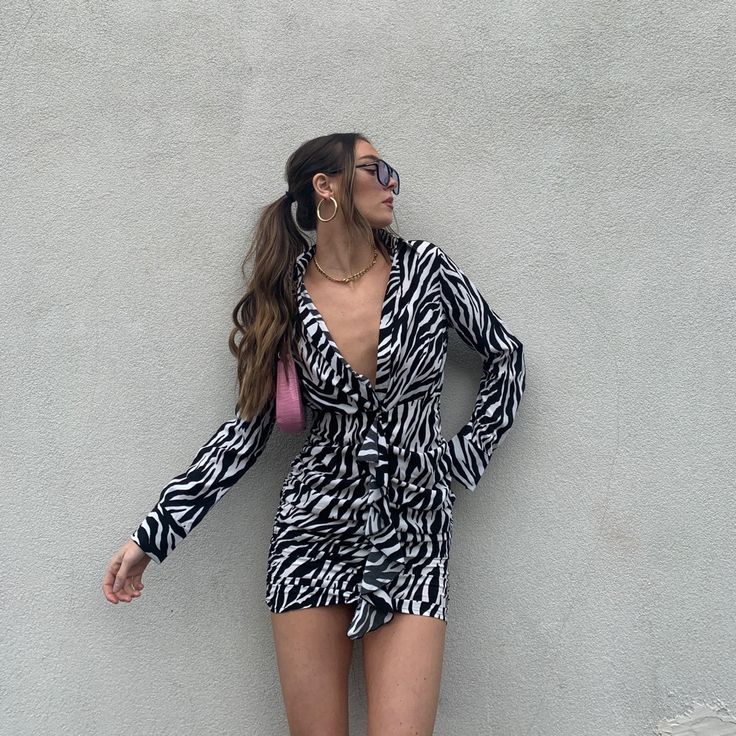 a woman in zebra print playsuit leaning against a wall