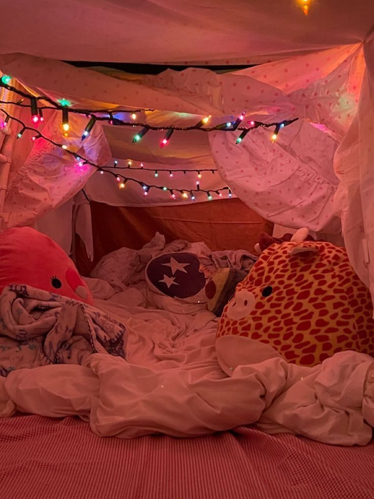 an unmade bed with colorful lights on the ceiling