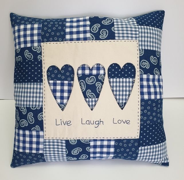 a blue and white pillow with three hearts on it that says live laugh love in the center