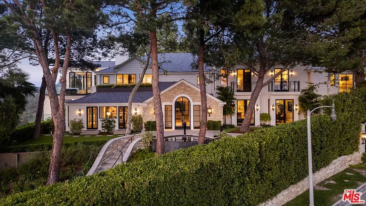 a large house with lots of windows and trees in front of it at night time