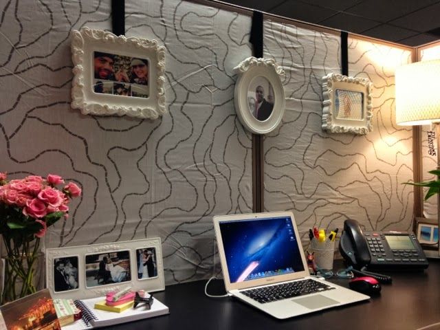 a laptop computer sitting on top of a desk next to a phone and pictures hanging on the wall