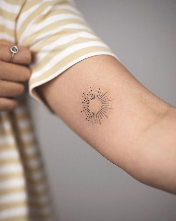 a woman's arm with a small sun tattoo on the left side of her arm