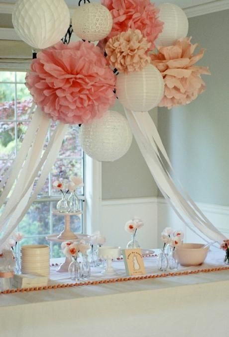 a table topped with lots of pink and white paper flowers on top of a table