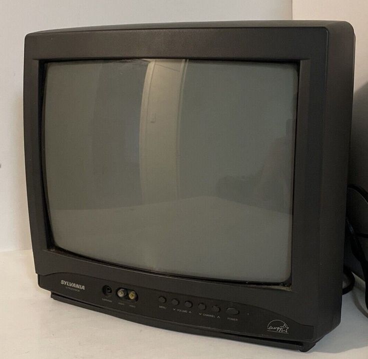 an old black television sitting on top of a white table next to a computer mouse