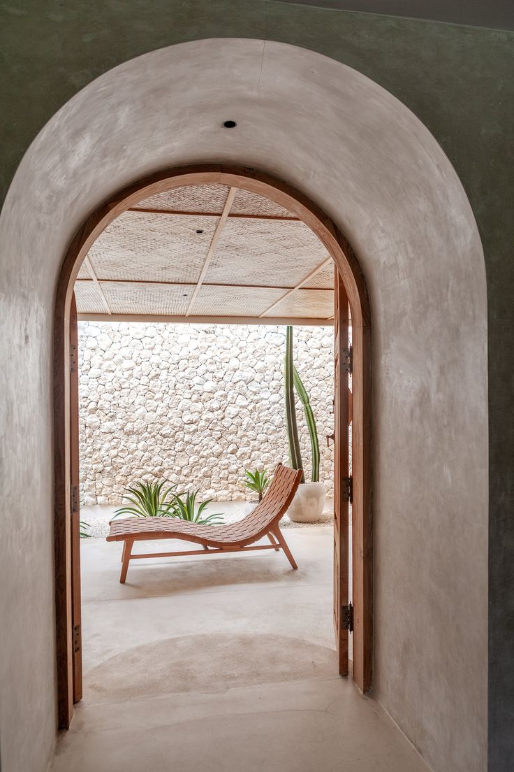 an arch leading into a room with a chair and potted plant