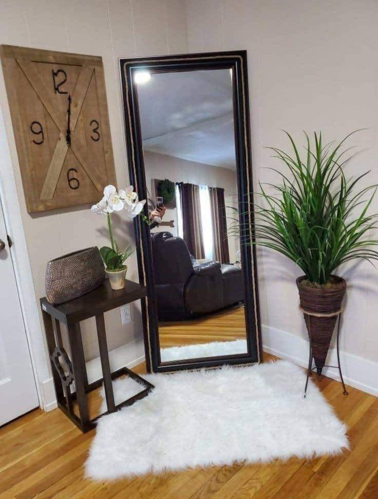 a large mirror sitting on top of a wooden floor next to a potted plant