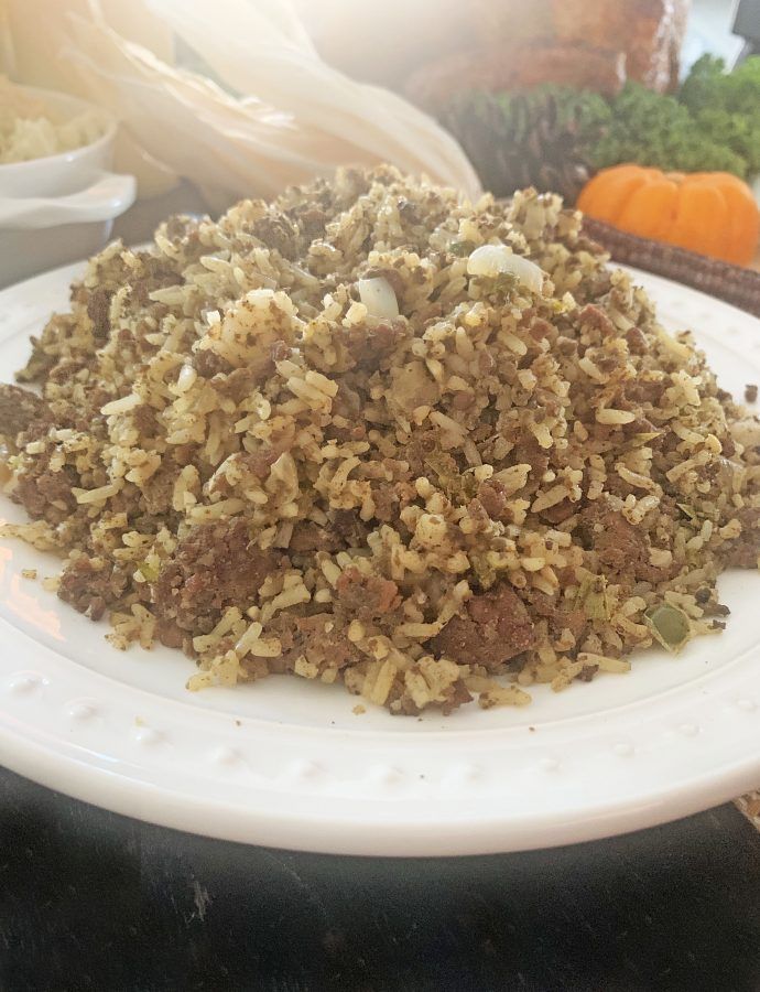 a white plate topped with lots of food on top of a table next to vegetables