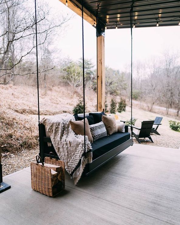 a porch swing with pillows and blankets on it