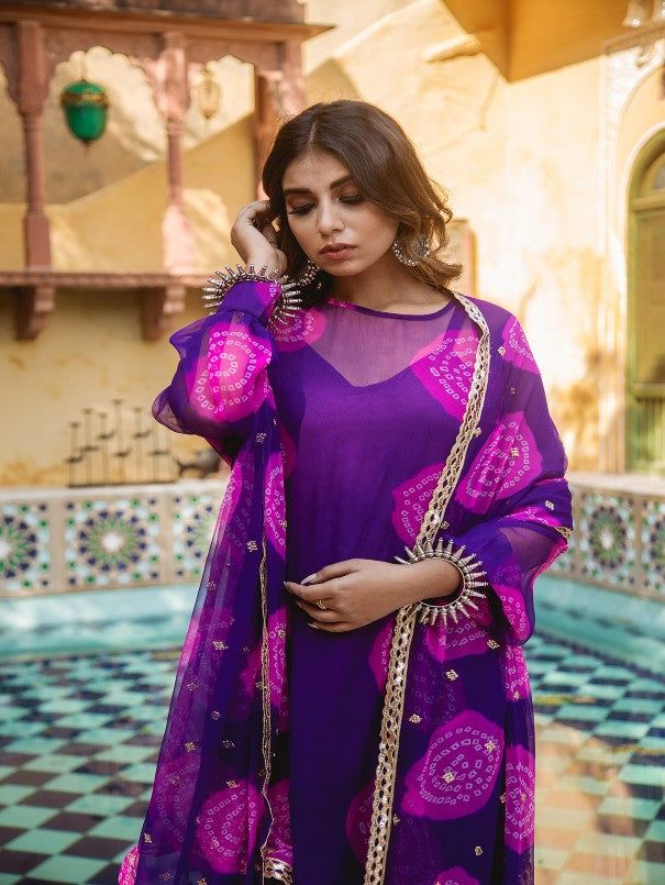 India is an embodiment of centuries of traditions and customs, that has a string of emotions attached. SATRANGI is an expression of joy and delight. The collection combines warmth of the blush reds with freshness of floral prints. Each color represents an attachment with the festivities, that is deeply rooted within all of us. Bandhej georgette set that is not to be missed. Paired with cotton pants and matching dupatta. It has lovely hand work, lace detailing on dupatta, finished with full lengt Gulabo Jaipur, Bandhej Suits, Bandhej Print, Cotton Palazzo Pants, Georgette Kurta, Sharara Designs, Bandhani Print, Kurta Palazzo Set, Mens Wear Wedding