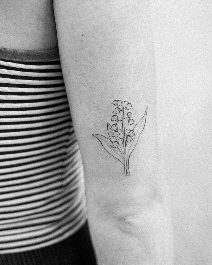 a black and white photo of a flower tattoo on the left upper half of the arm