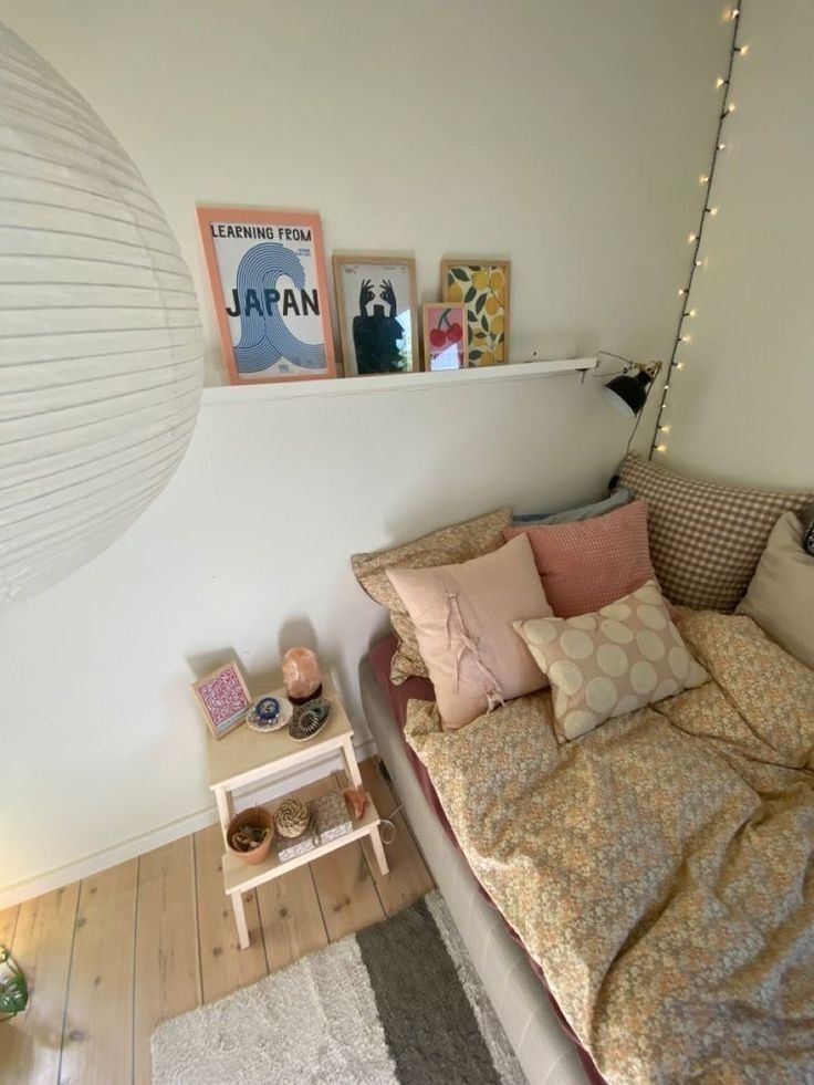 a bed with pillows and blankets on top of it next to a night stand in a room