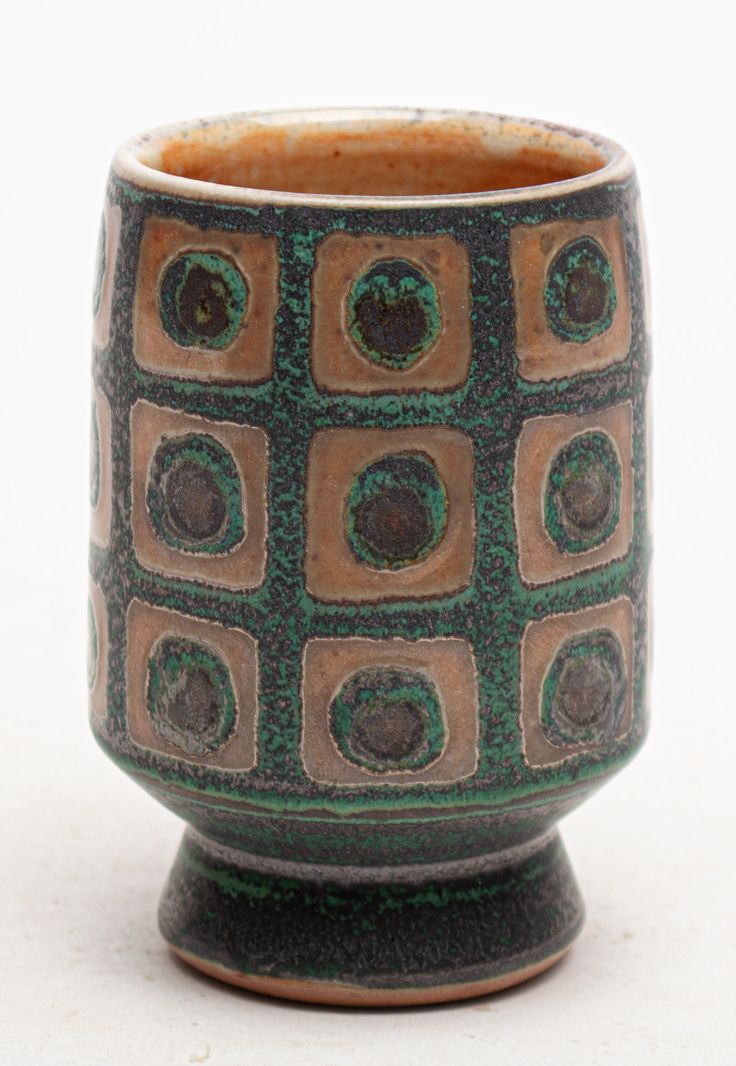 a brown and green cup sitting on top of a table