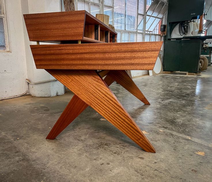 a wooden table sitting on top of a floor next to a window in a building