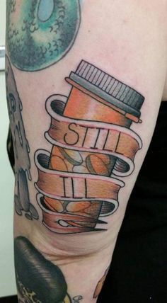 a person with a tattoo on their arm has a stack of books and a donut