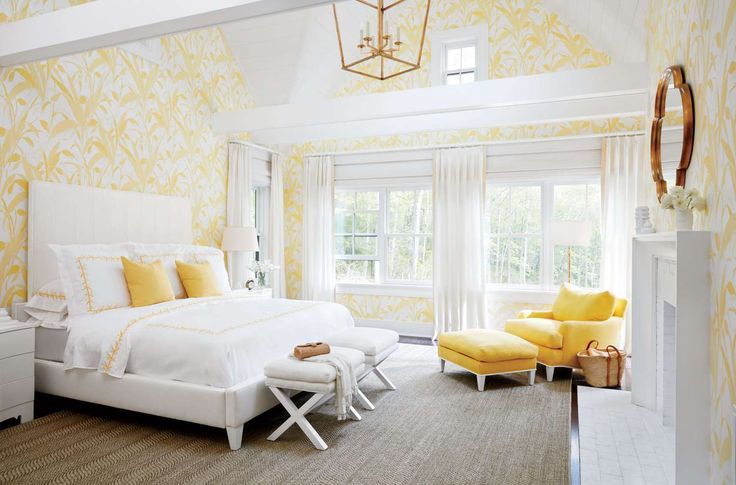 a white bed sitting in a bedroom next to two yellow chairs and a lamp on top of a table