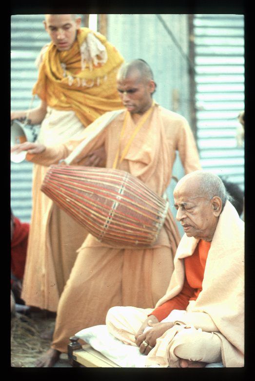 an old man sitting in front of another man with a basket on his lap and two other men standing behind him