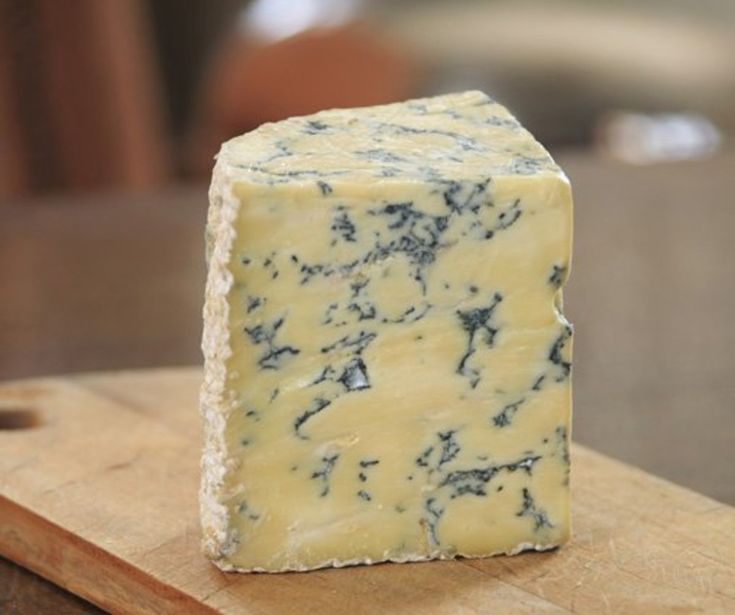 a block of blue cheese sitting on top of a wooden cutting board