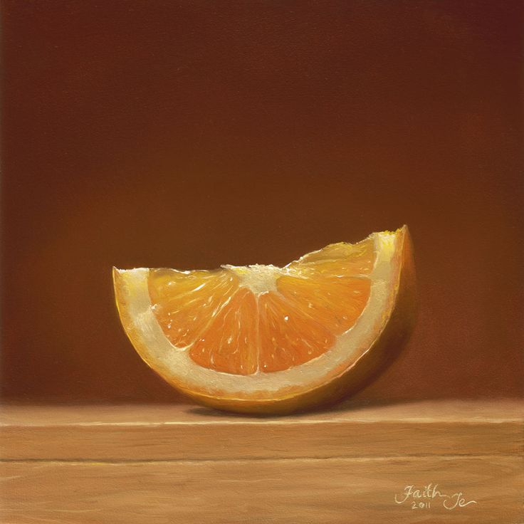 an orange cut in half sitting on top of a wooden table next to a brown wall