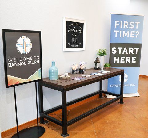 two signs are displayed on the wall next to each other in front of a wooden table