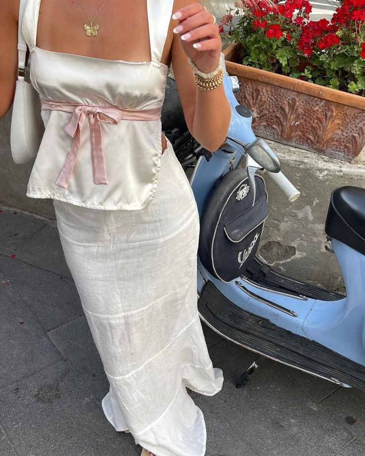 a woman in a white dress standing next to a scooter