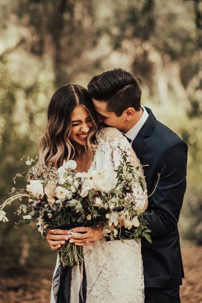 a bride and groom embracing each other in the woods with flowers on their wedding day