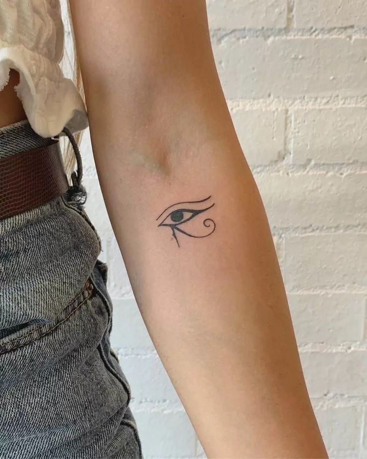 a woman's arm with an eye tattoo on the left side of her arm