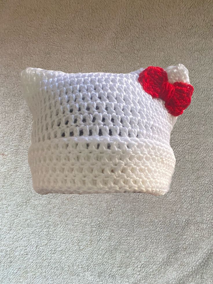 a white crocheted pillow with a red heart on it