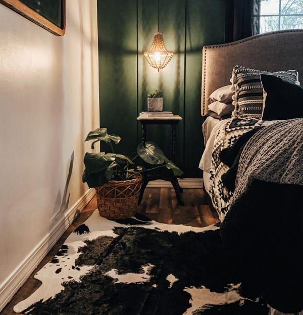 a bedroom with dark green walls and cow hide rug