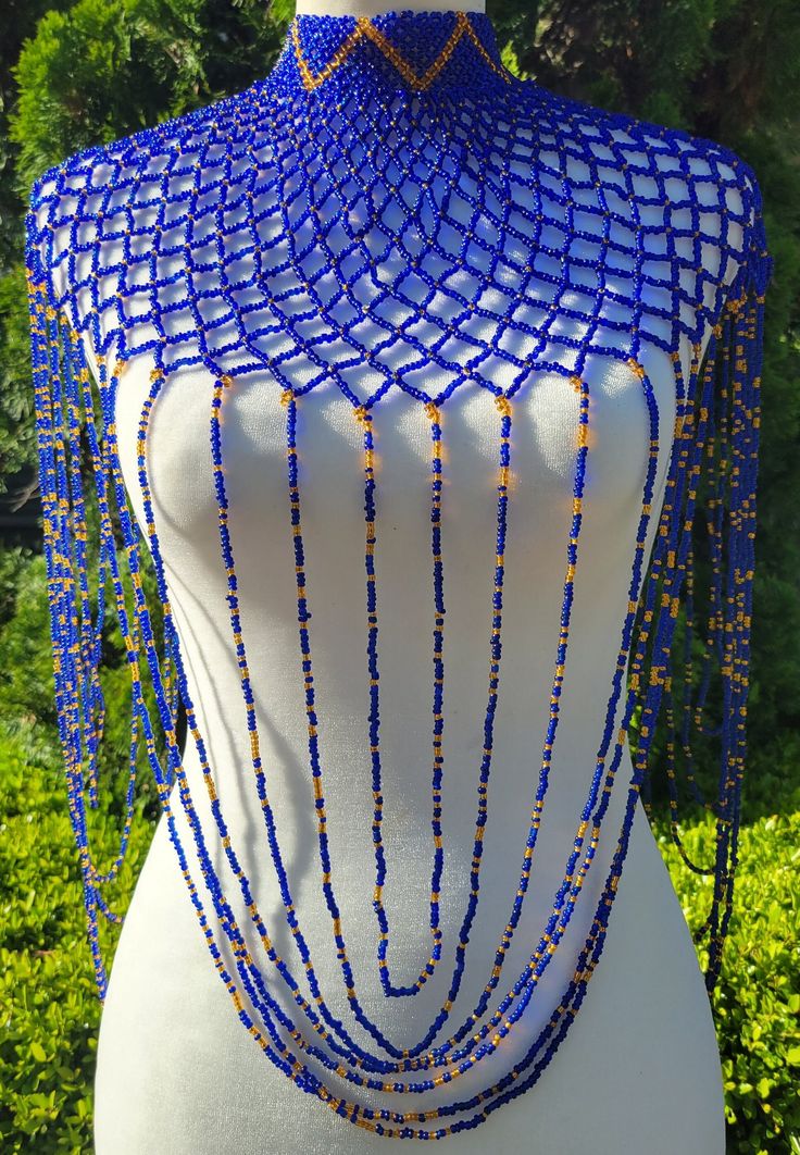 Beautifully beaded high collar body necklace. Primary color is royal blue with gold beads placed throughout a diamond shaped web design with loop accents. The fit of this necklace is a high choker cascading down the chest with delicate loop details draping the arms and torso. Body necklace measurements are as followed: The front is 14.5 inches long (measured from top of the chocker neckline down the front of the torso.  The side is 13.5 inches long (measured from shoulder and down the arm) and the diameter of the portion just around the neck is 5.5 inches (measured when closed using the middle toggle / loop). The back closure is made from 2 beaded toggles that can fit into 3 different loops to adjust diameter around the neck. Blue Beaded Choker For Party, Blue Beaded Necklaces For Evening, Elegant Blue Choker For Festivals, Blue Beaded Bib Necklace For Party, Beads Clothes, Necklace Measurements, Avatar James Cameron, Body Necklace, Gold Bodies