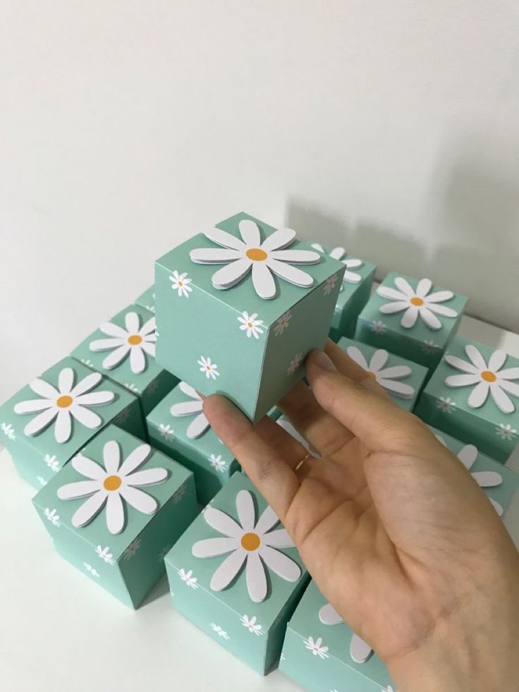 a hand is reaching for several small boxes with daisies on them