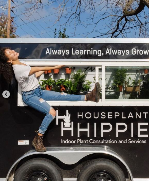 a woman leaning out the window of a houseplant hippie truck