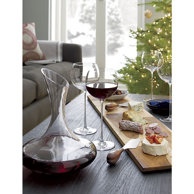 two glasses of wine, cheese and crackers on a table with a christmas tree in the background