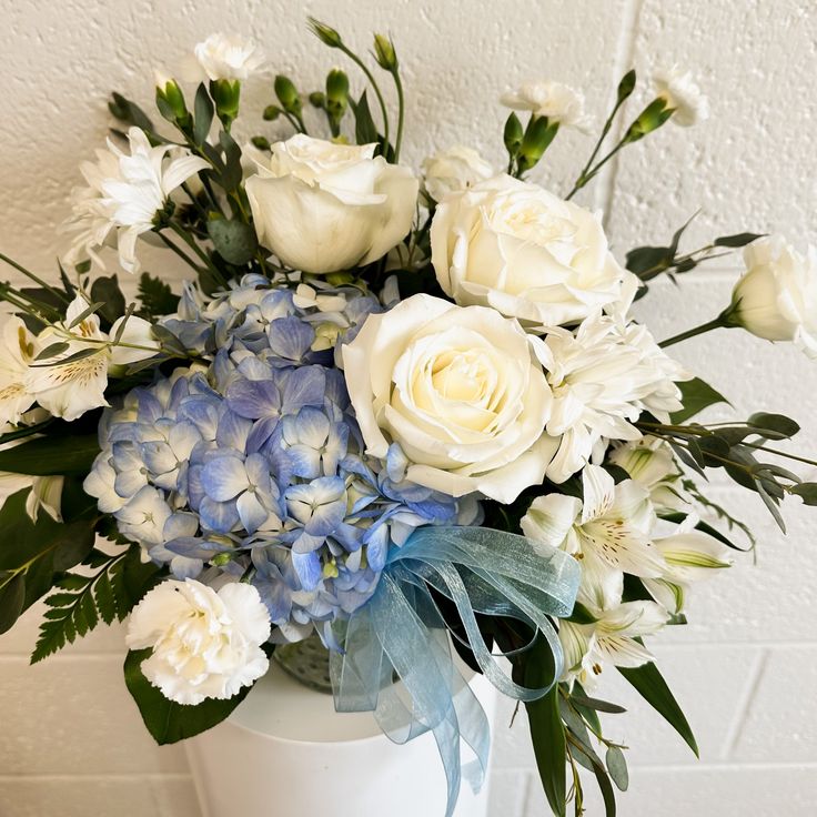 a bouquet of white and blue flowers in a vase