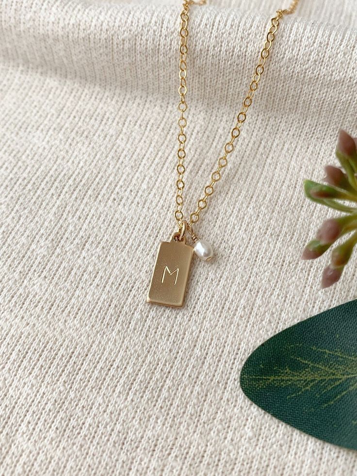 This dainty monogram necklace can be personalized for yourself or to give as a thoughtful gift! Each tiny rectangle charm is hand stamped with the initial of your choice, and accented with a tiny natural pearl (other gems available upon request.) This makes a gorgeous simple and meaningful every day necklace. * Tiny 14K Gold Filled or 925 Sterling Silver 13x6mm rectangle tag charm * Tiny Freshwater Pearl charm * 14K Gold Filled or 925 Sterling Silver Chain & spring ring clasp * Choose your lengt Gifts For Sister Birthday, Every Day Necklace, Initial Tag Necklace, Sister Birthday Gift, Rectangle Necklace, Dainty Initial Necklace, Dainty Gold Necklace, Monogram Necklace, Keepsake Jewelry