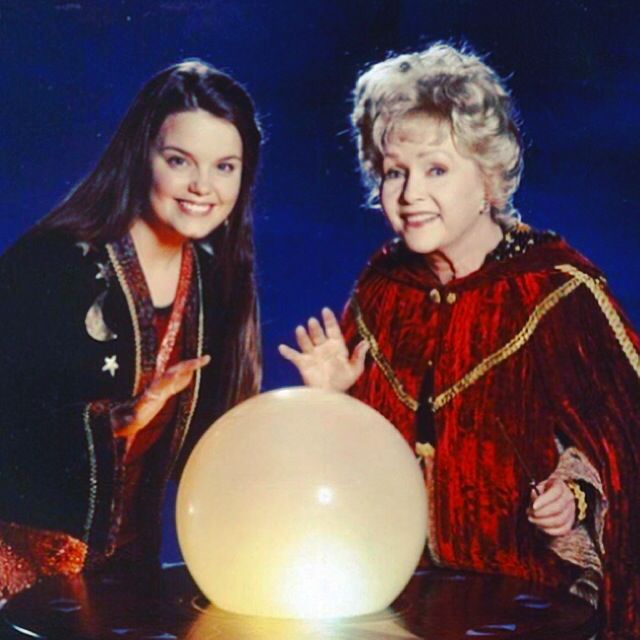 two women standing next to each other in front of a white ball on a table