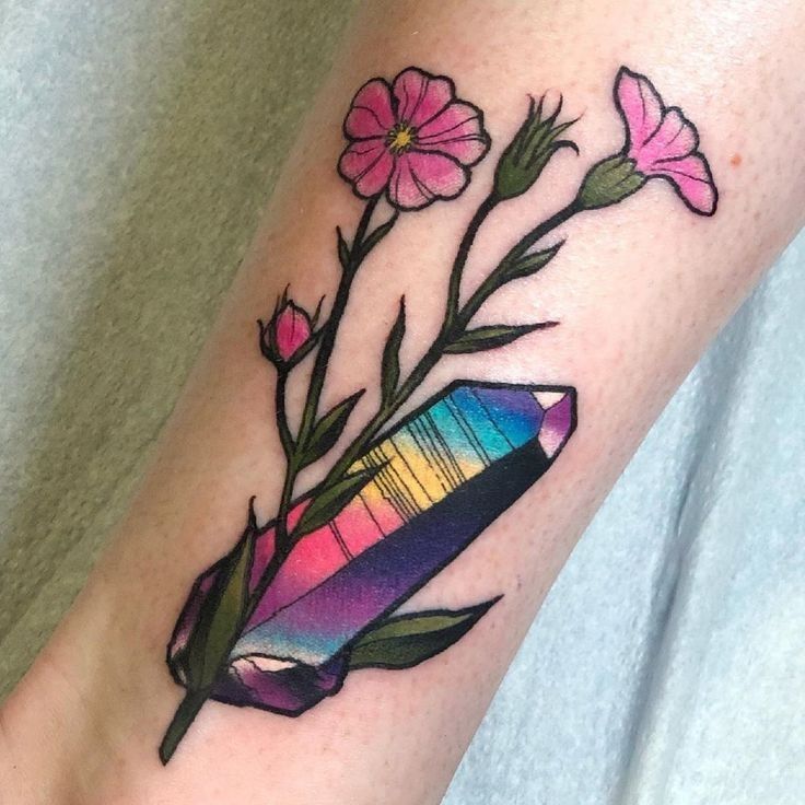 a colorful tattoo on the leg of a woman with pink flowers and a pencil in it