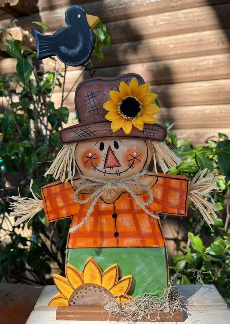 a scarecrow with a sunflower on its head and a bird perched on it