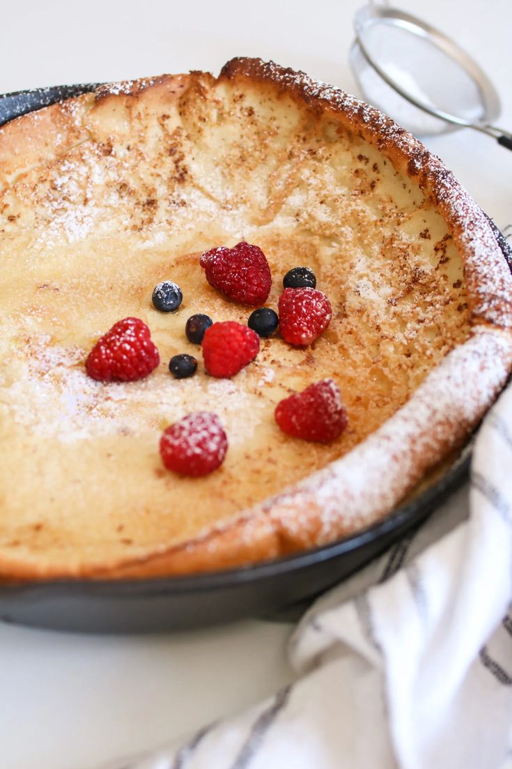 a pancake with berries and powdered sugar on top