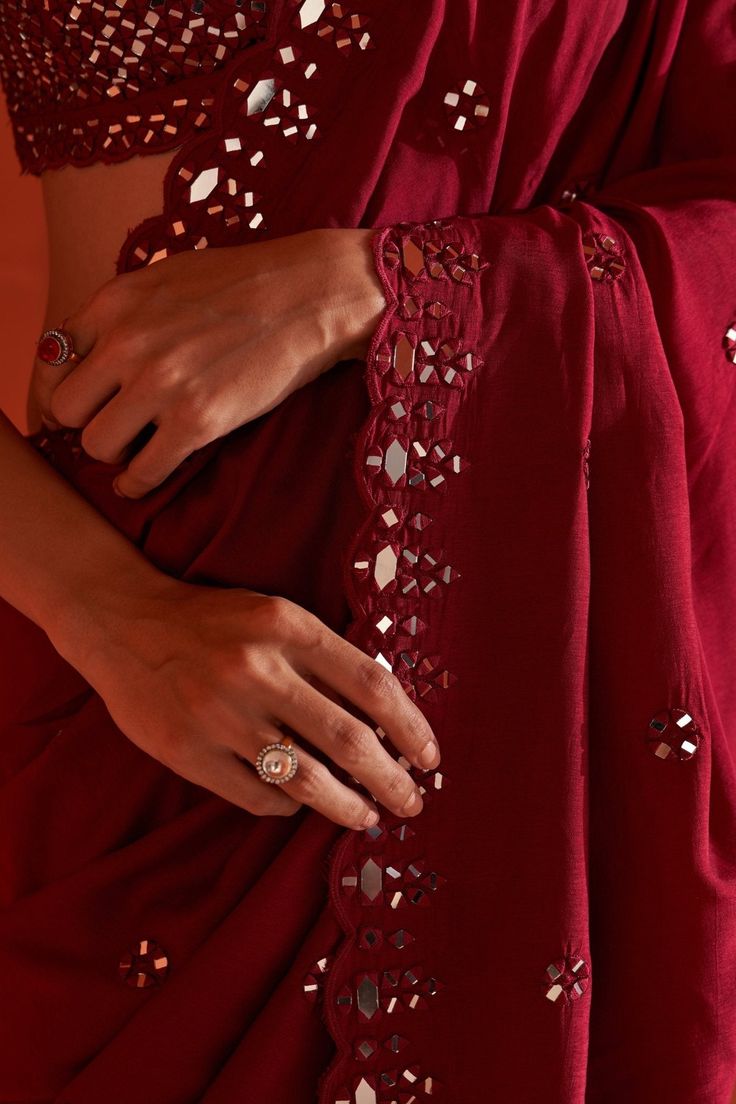 Featuring a maroon silk saree embellished with mirror and tonal silken thread work. It is paired with a sleeveless blouse with mirror and thread work in jaal pattern along with tassel tie-up at the back.Composition : Saree & Blouse: SilkCare: Dry Clean Only and Vacuum Storage All products can be customised for sleeves, length of blouse and neck design Delivery : 4-6 weeks as the product is hand crafted. Check Size Guide or choose MySize for free customisation (All Sizes above XL can be made at 15% additional cost) For more information and sizes please contact fabiliciousfashion@gmail.com or visit our Copenhagen studio.About the Designer : Angad Singh's journey in the world of fashion started with at an early age as he grew up in a family business that was immersed in couture. Seeking to ex Deep Maroon Silk Saree, Deep Maroon Saree, Machine Mirror Work Embroidery, Mirror Work On Saree, Mirror Work Saree Designs, Cut Work Sarees, Maroon Silk Saree, Mirror Work Sarees, Mirror Work Saree Blouse