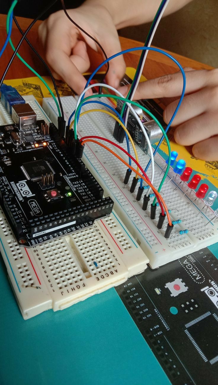 two hands are working on an electronic device that is connected to breadboard and wires