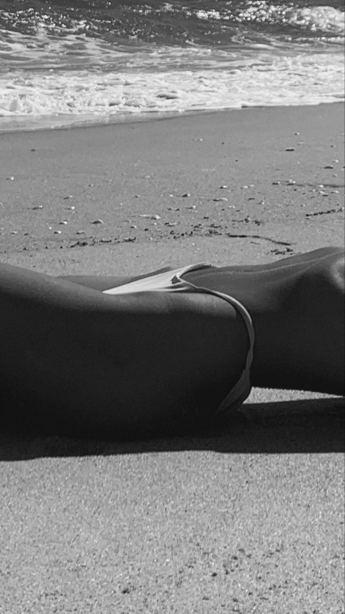 a person laying on the beach with their feet in the sand